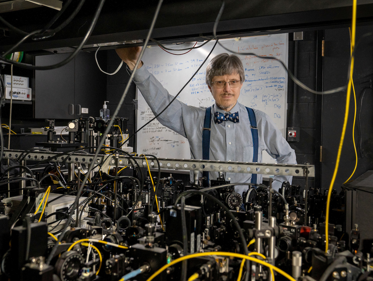 Paul Kwiat stainding in his lab, framed by lab equipment.