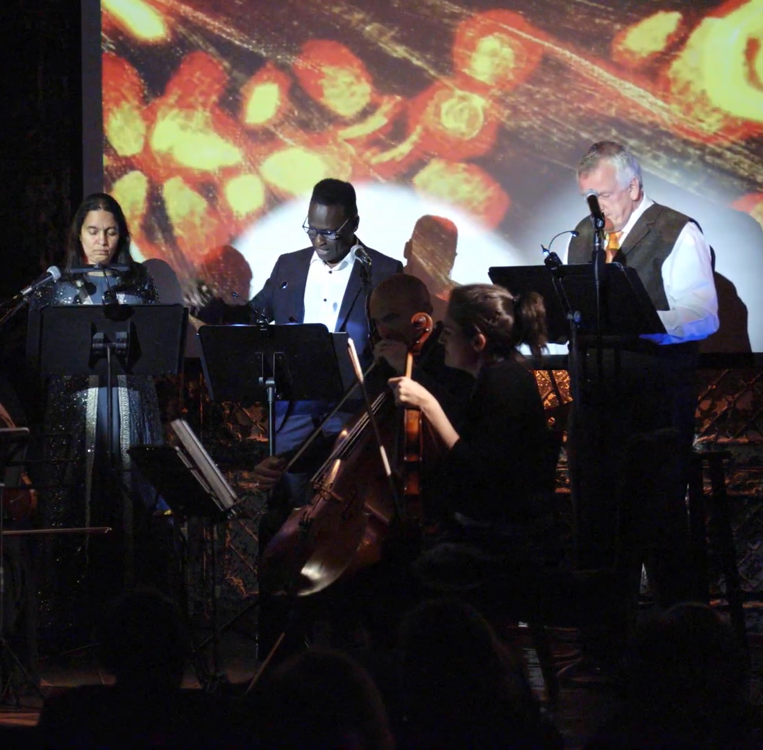 Three people are highlighted by spotlight on stage