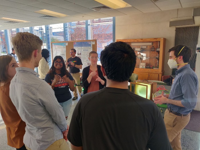Colin Lualdi (right), and other graduate students explain the properties of light, including polarization, to World Quantum Day guests.