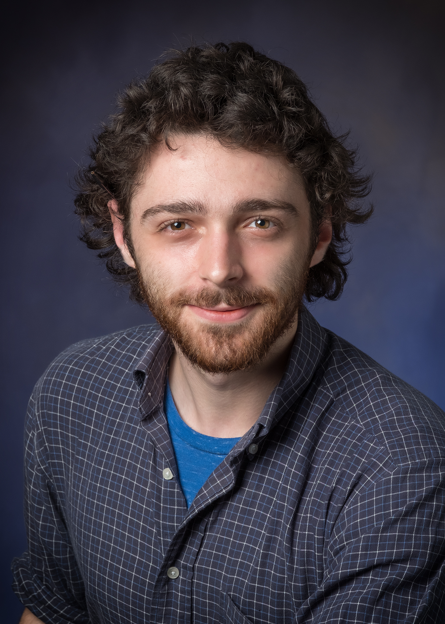 Photo shows man with dark curly hair smiling