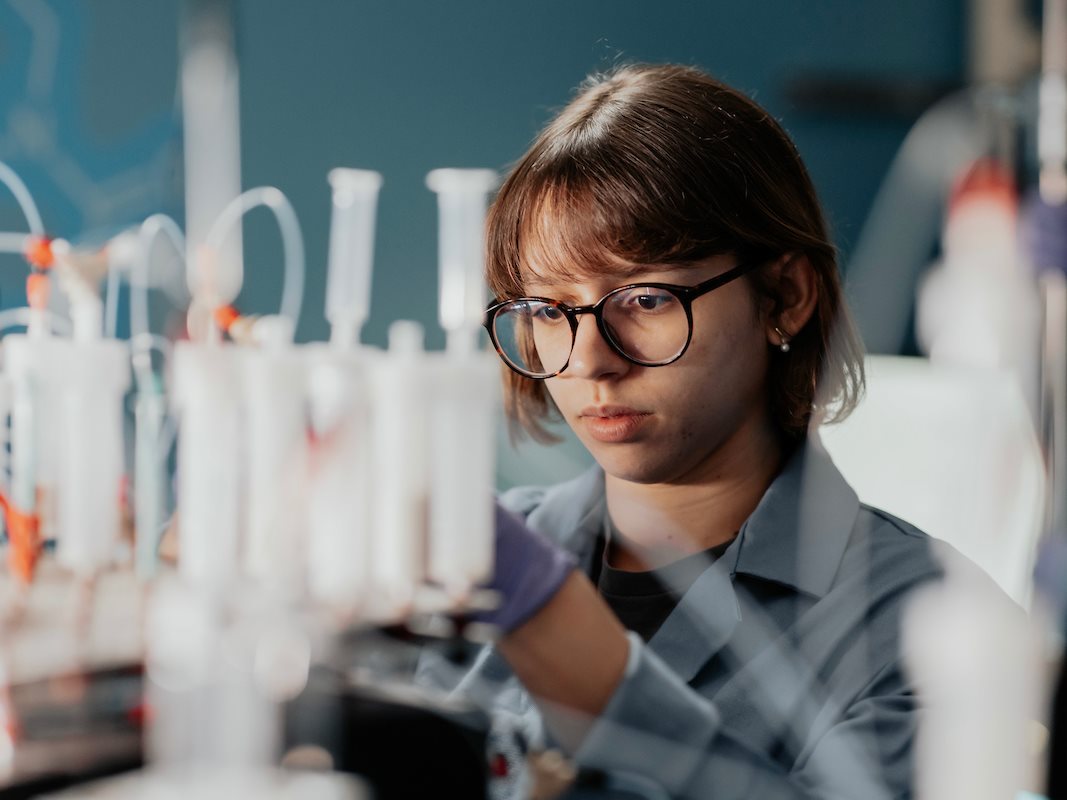 Student surrounded by test tubes in Molecular Maker research lab.