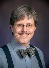 A man with a bow tie, gray hair, and glasses